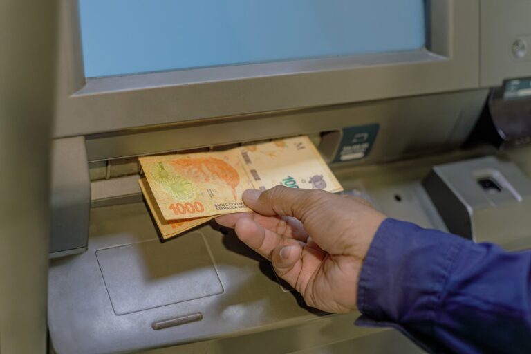 Sucursal bancaria con cartel de cerrado y teléfono móvil mostrando una aplicación de home banking activa.