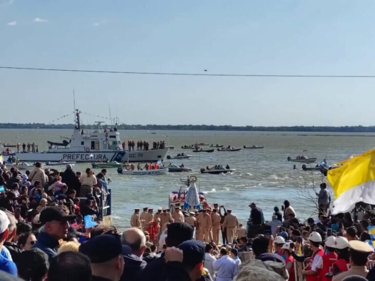 Procesión náutica de las imágenes de la Virgen de Itatí y la Virgen de Caacupé en el río Paraná, con fieles en la costa de Itatí